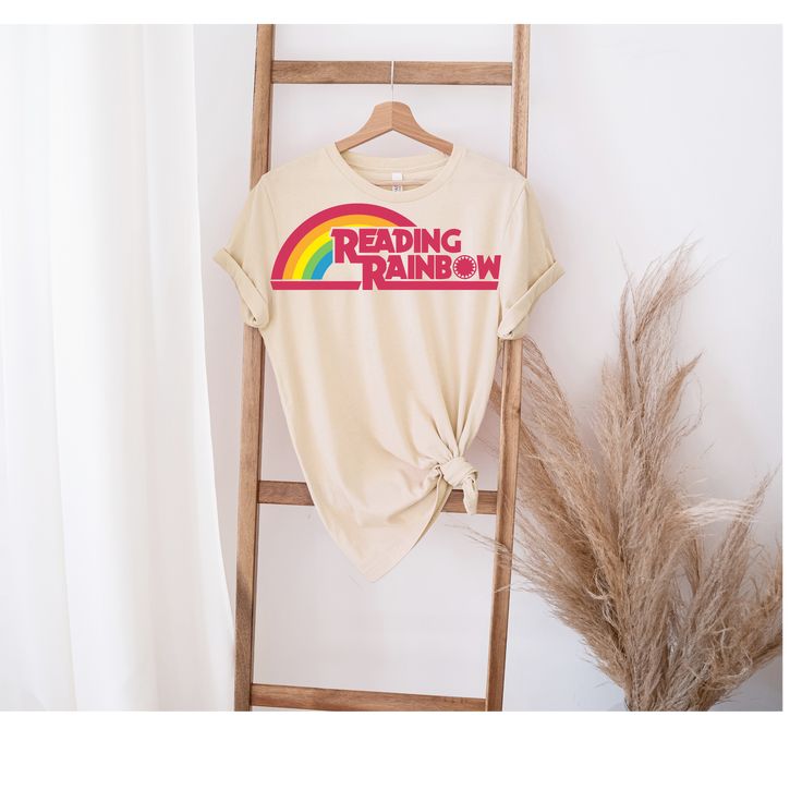 a t - shirt that reads reading rainbow on it next to a ladder with dried grass