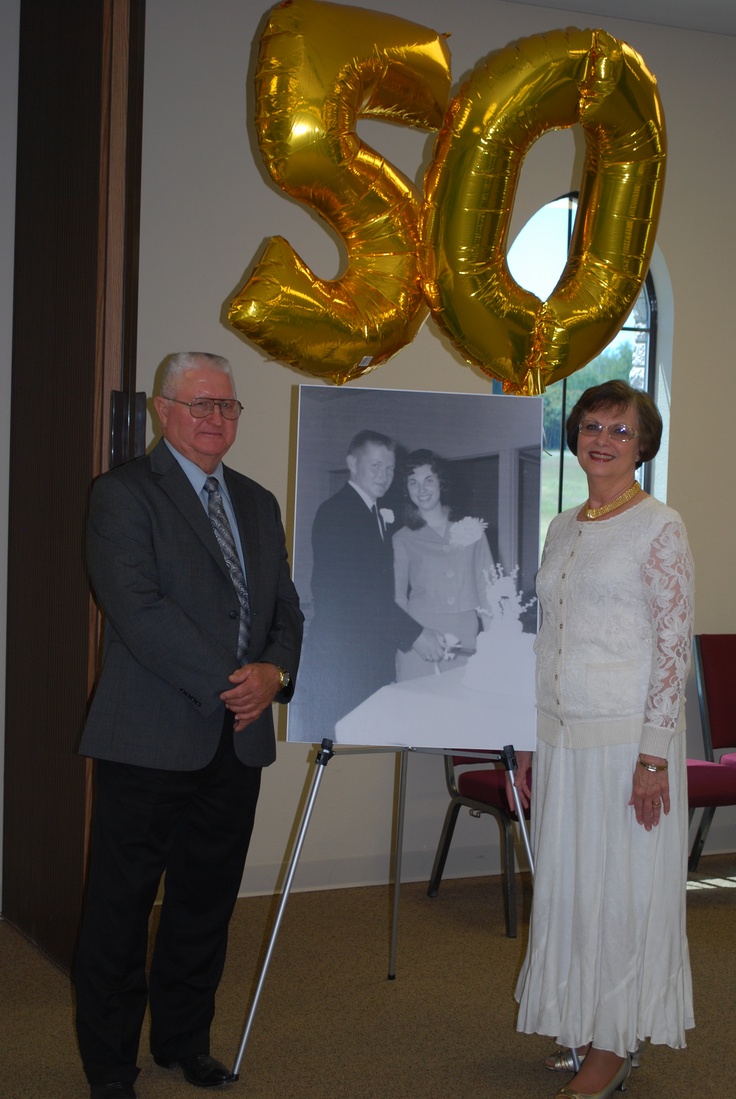 a man and woman standing in front of a large balloon with the number 50 on it