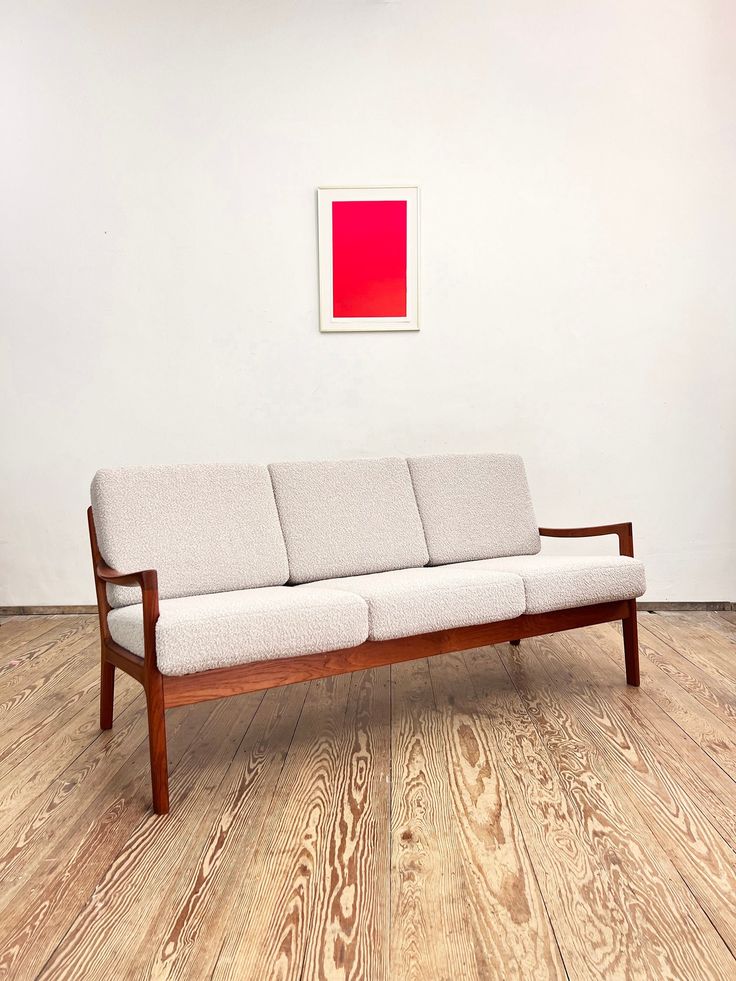 a couch sitting on top of a hard wood floor next to a red square painting