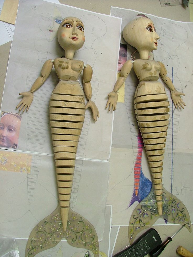 two wooden dolls made to look like they are standing next to each other on paper