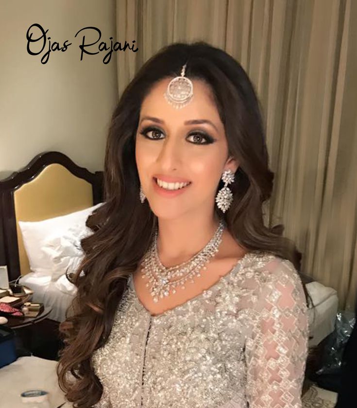 a beautiful woman in a white dress posing for the camera with jewelry on her head