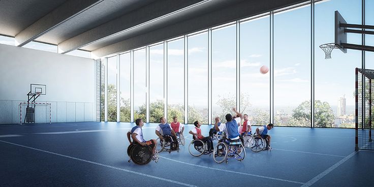 several people in wheelchairs are playing basketball on an indoor court with glass walls and large windows