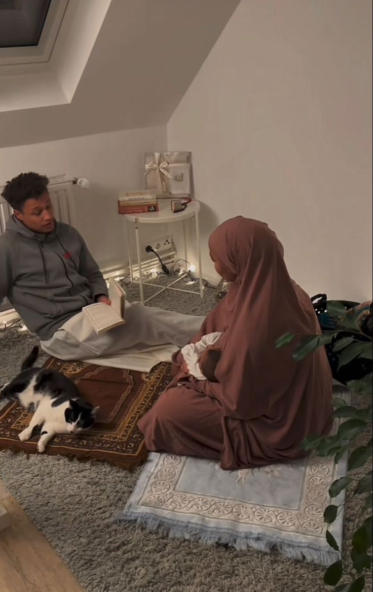 two people sitting on the floor with a cat