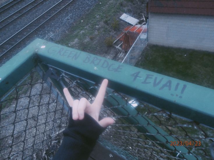 someone is holding their hand up to the fence that says, green bridge evau