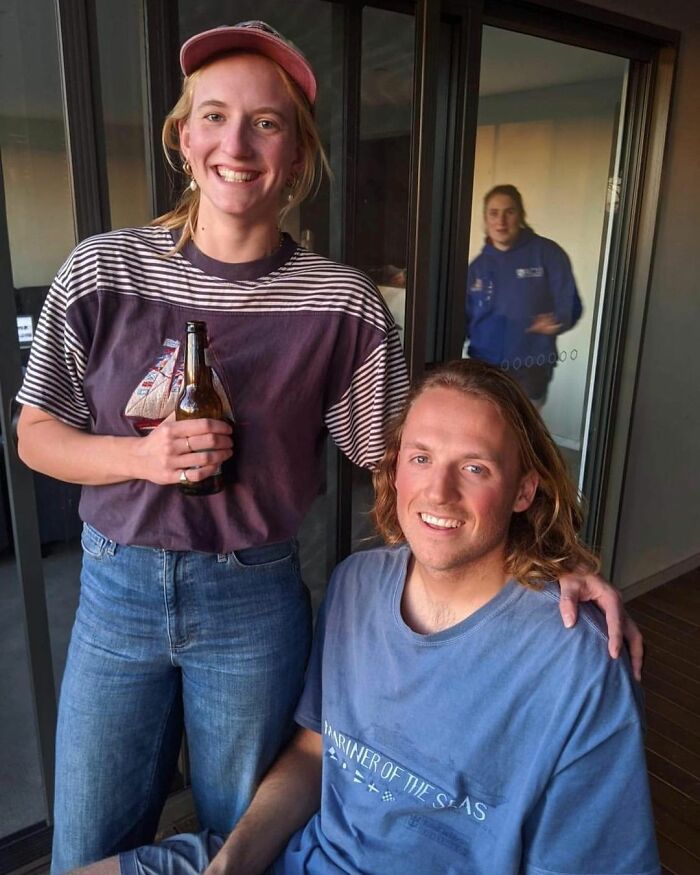 two people standing next to each other with beer in their hands and one person sitting on the ground