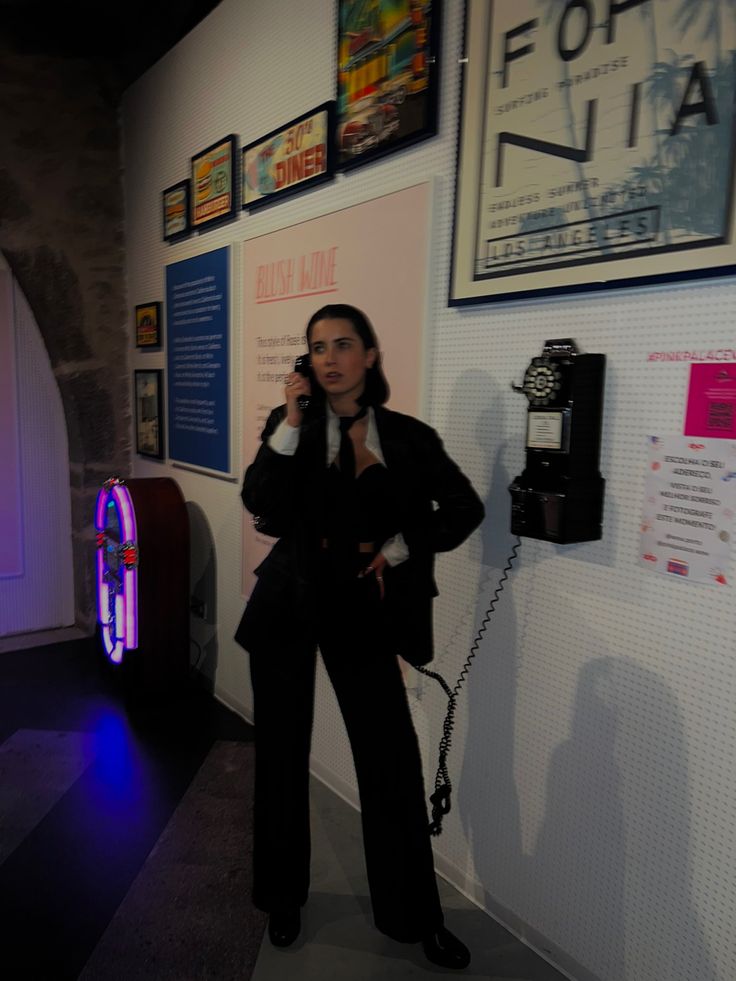 a woman standing in front of a wall talking on a cell phone