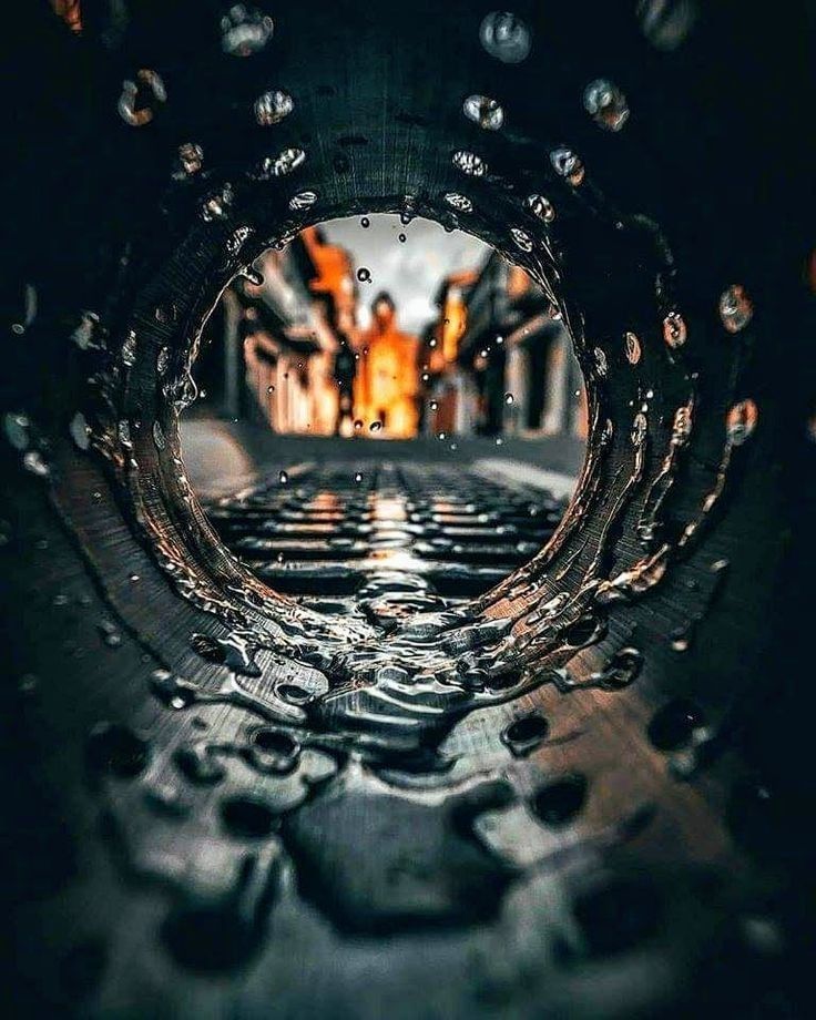 the inside of a metal pipe with water droplets on it and people in the background