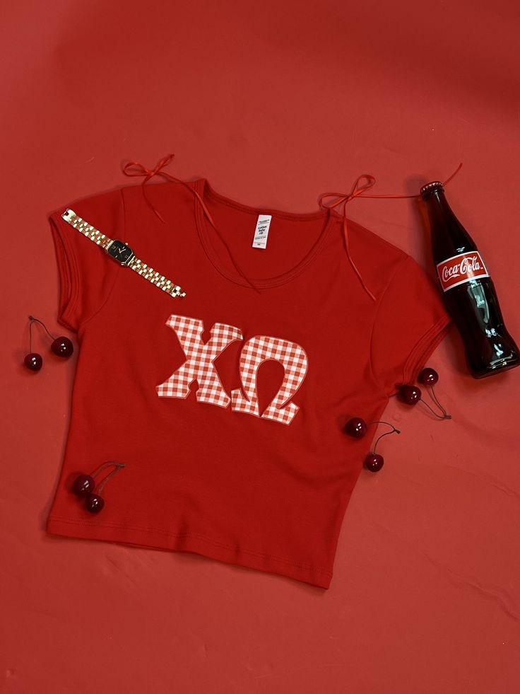 a red shirt with the letters xo on it next to a bottle of beer