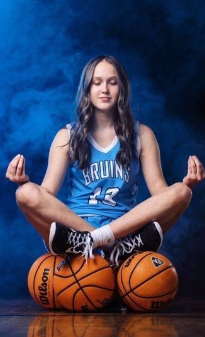 a woman sitting in the middle of a basketball pose