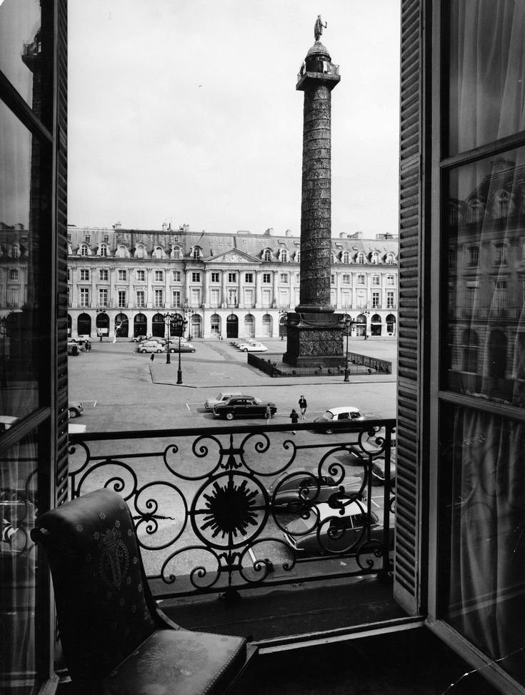 an open window with a view of a street and a clock tower in the distance