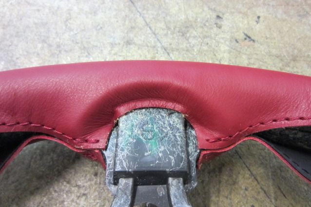 the inside of a red leather seat on a car's steering wheel, which is being repaired