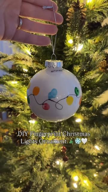 a hand holding a christmas ornament on top of a tree