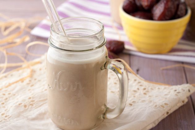 a glass jar filled with milk next to a bowl of cherries