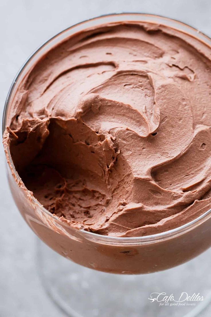 a close up of a dessert in a glass with chocolate frosting on the top