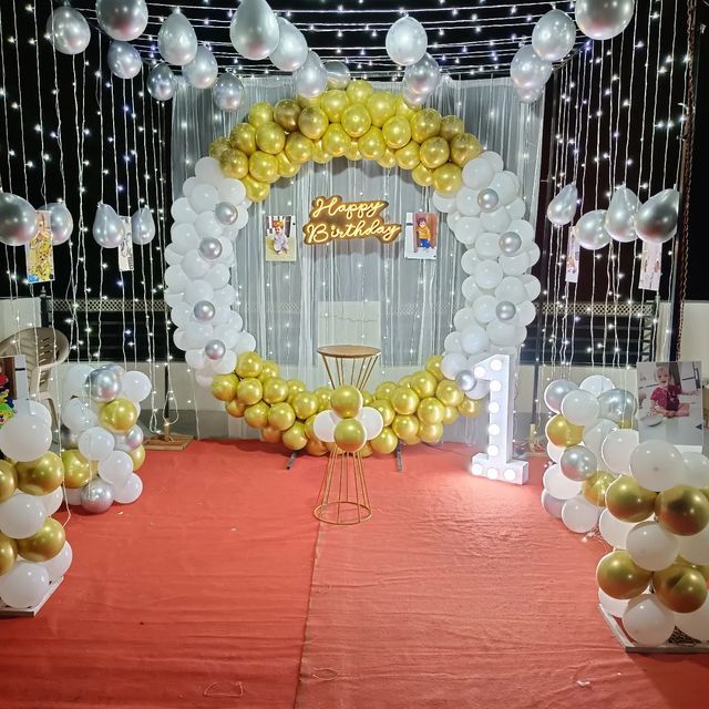 balloons and streamers are set up on the floor for a birthday party with white, gold and silver decorations