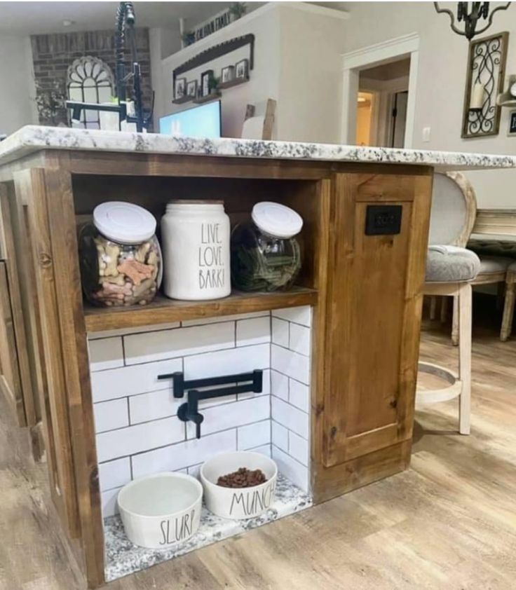 an open cabinet in the middle of a kitchen with two bowls and one bowl on it