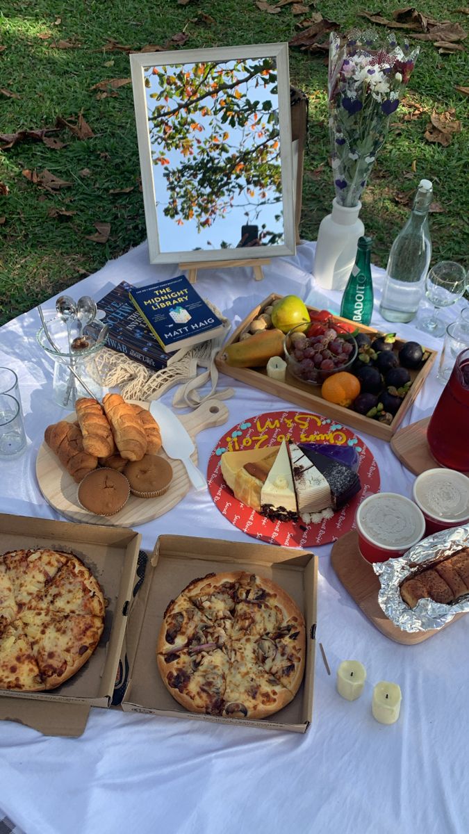 a table topped with pizzas and other food items on top of a white table cloth