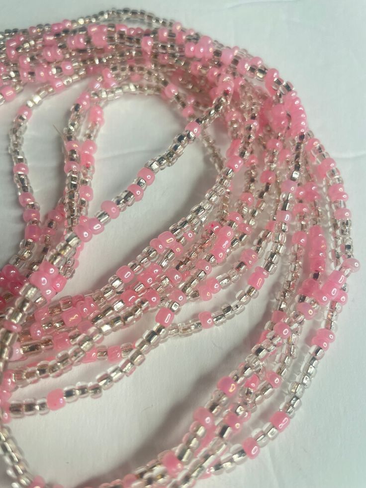 Elastic Waist Bead "Diawala" features strands of clear and silvery glass seed beads, elegantly adorned with delicate baby pink seed bead accents. Elevate your style with the timeless beauty of this harmonious blend, offering a touch of sophistication and gentle femininity. 💫 Clear and Silvery Radiance: This elastic waist bead gleams with clarity, adorned with clear and silvery glass seed beads that reflect a subtle, luminous radiance. The combination creates a versatile backdrop, allowing the a Pink Beaded Bracelets With Polished Round Beads, Pink Bohemian Waist Beads With Colorful Beads, Pink Spiritual Beaded Bracelet With Polished Beads, Spiritual Pink Beaded Bracelets With Polished Beads, Pink Tiny Beads Waist Beads For Gift, Adjustable Pink Waist Beads With Spacer Beads, Silver Tiny Beads For Festival, Pink Spacer Beads For Beach, Pink Spacer Beads For Festival