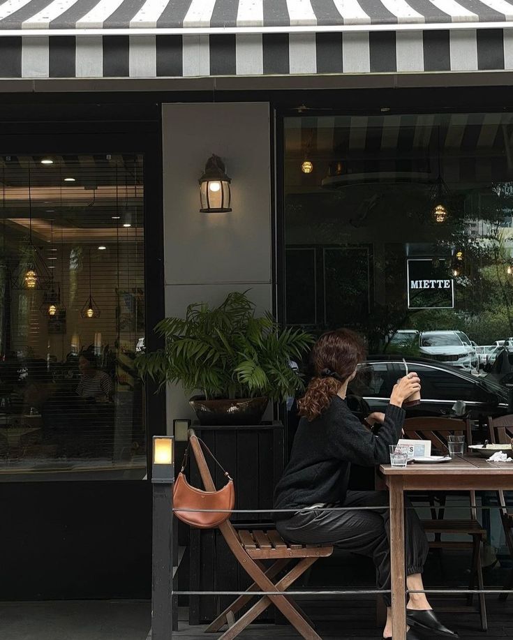 a woman sitting at a table in front of a restaurant