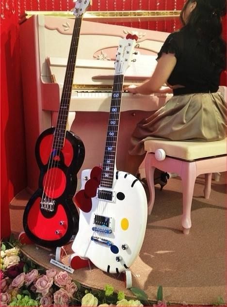 two guitars sitting on top of a table in front of a desk with flowers and hello kitty decorations