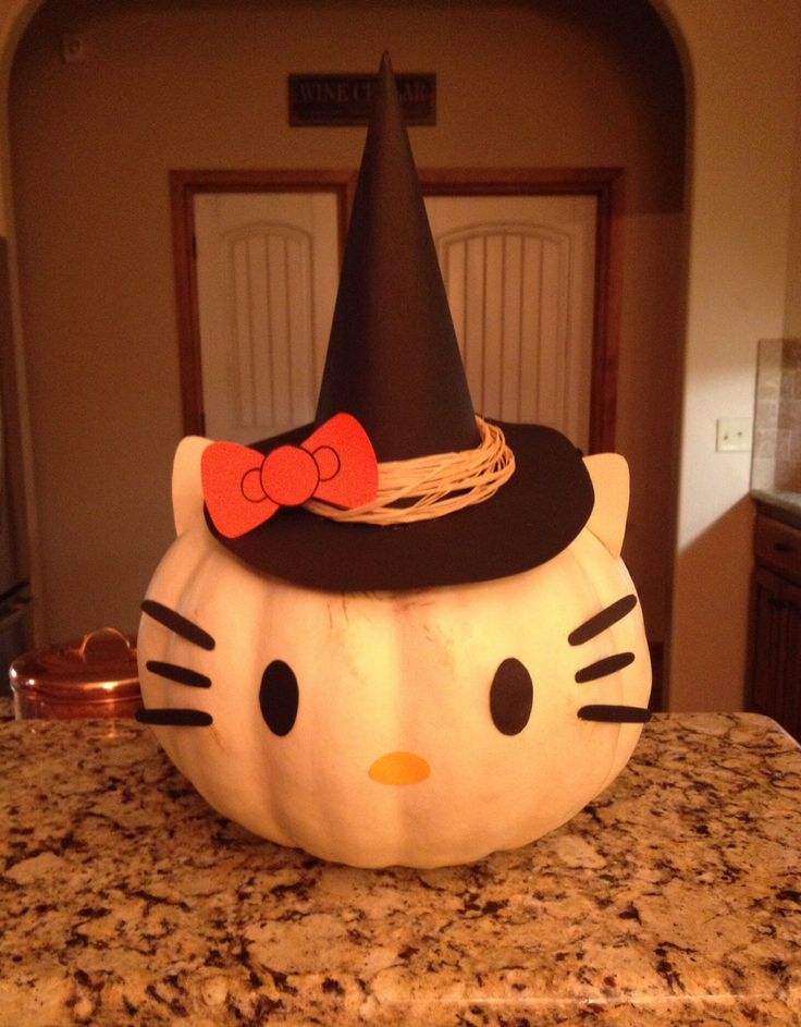 a hello kitty pumpkin sitting on top of a kitchen counter with a black cat hat