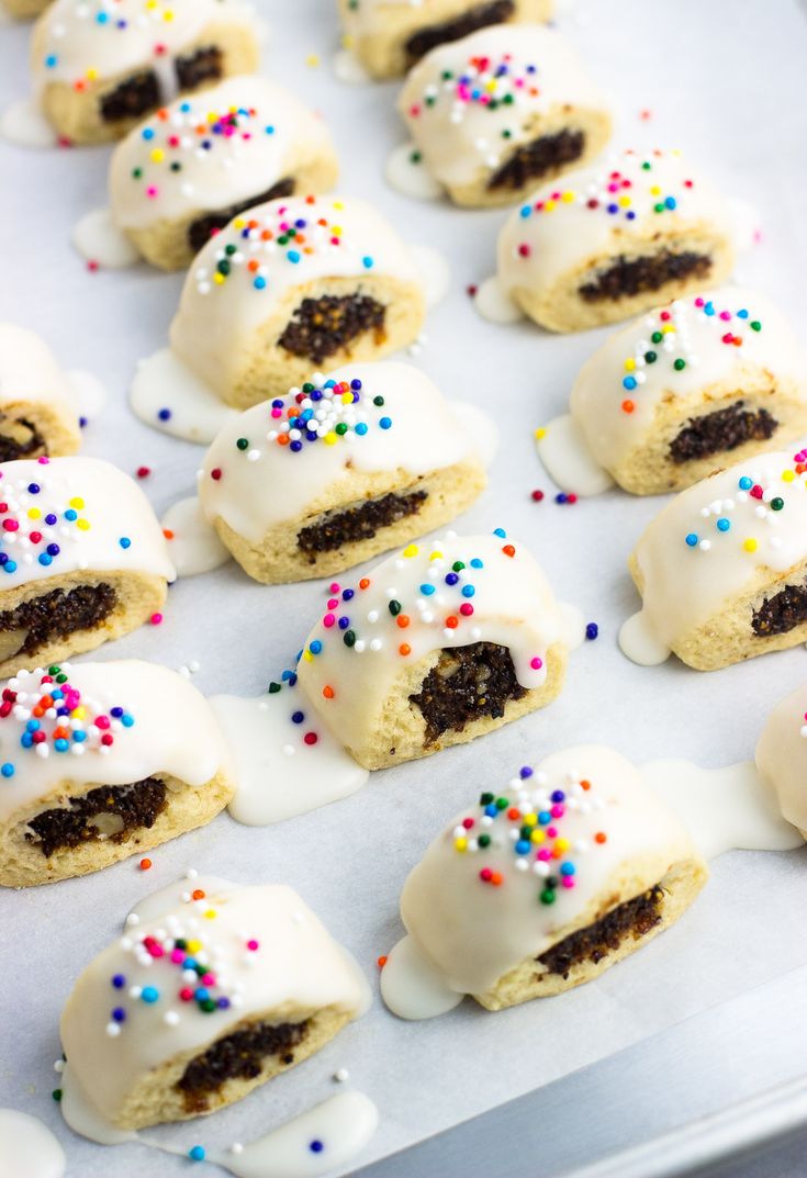 cookies with white frosting and sprinkles on a baking sheet covered in icing