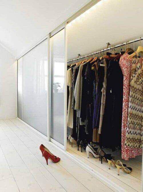 a woman's red high heeled shoe sitting on the floor in front of a closet full of clothes