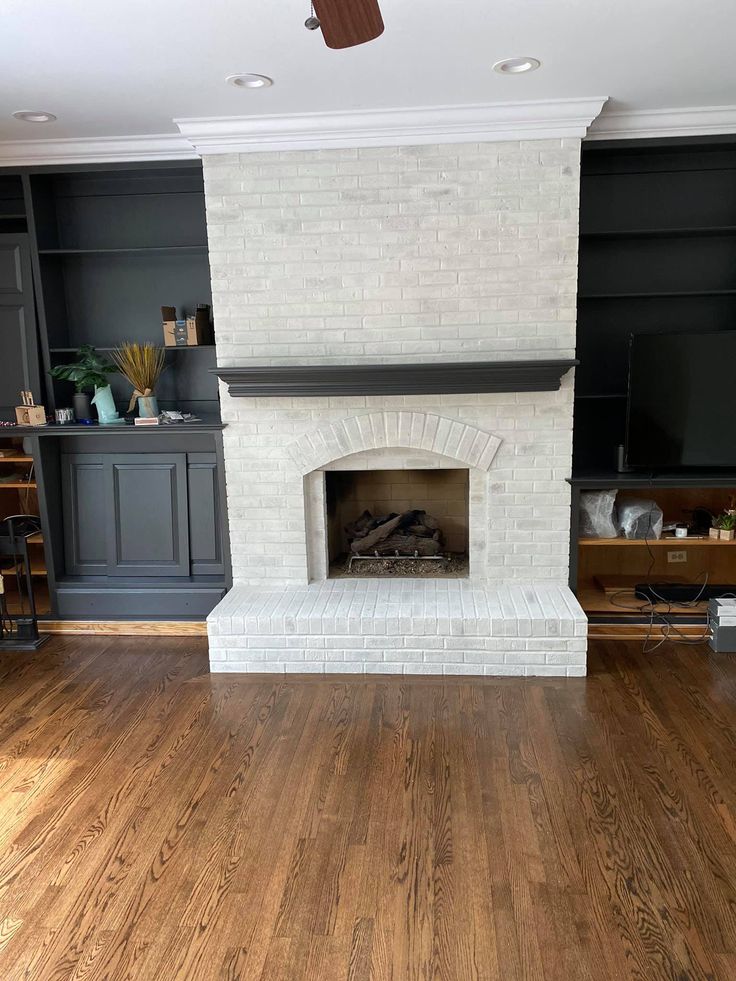 a living room with wood floors and white brick fireplace