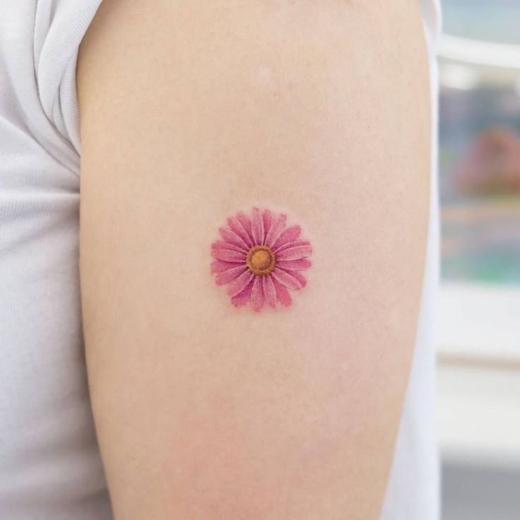 a small pink flower on the back of a woman's arm