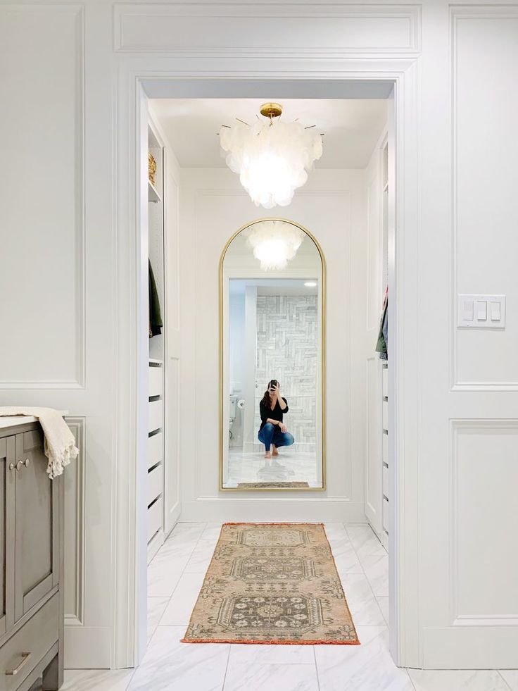 a woman taking a selfie in a mirror on the wall next to a rug