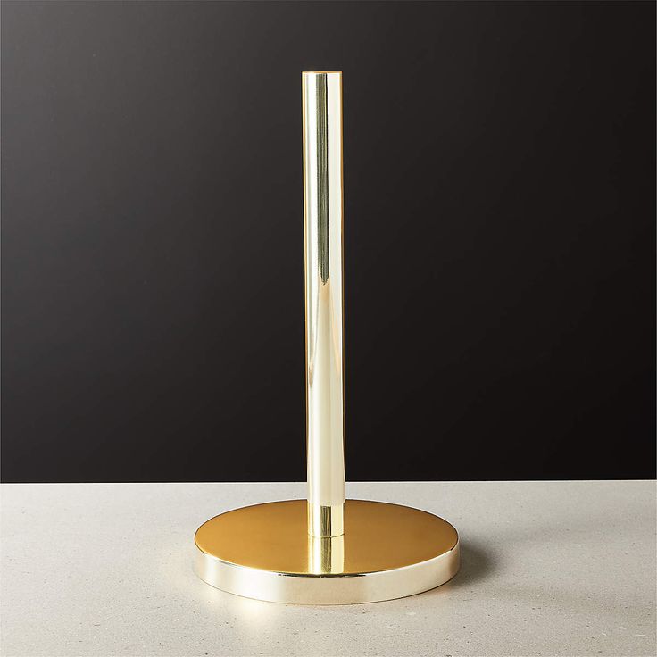 a gold plated table lamp on a white surface with a black wall in the background