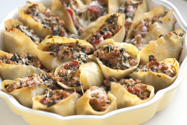 a casserole dish filled with stuffed shells and meats, ready to be eaten