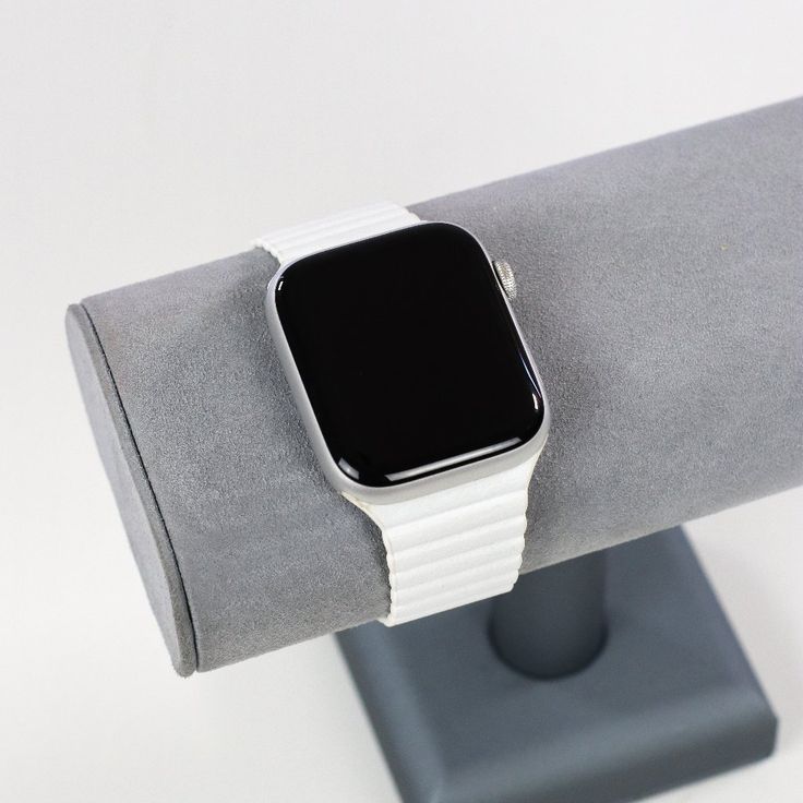 an apple watch is sitting on top of a gray cloth holder with a black and white strap