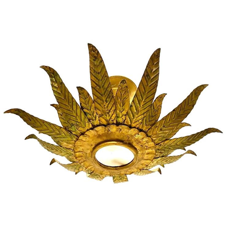 a gold ceiling light with green leaves on it's side and a white background