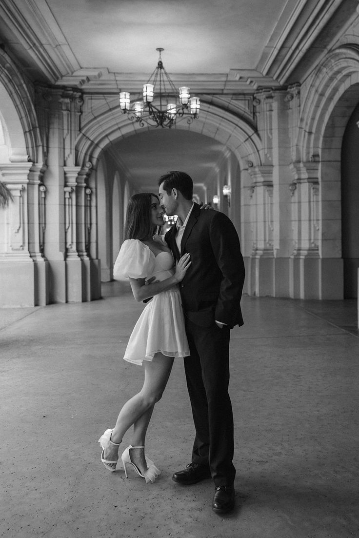 a man and woman are standing together in an empty room with chandeliers hanging from the ceiling