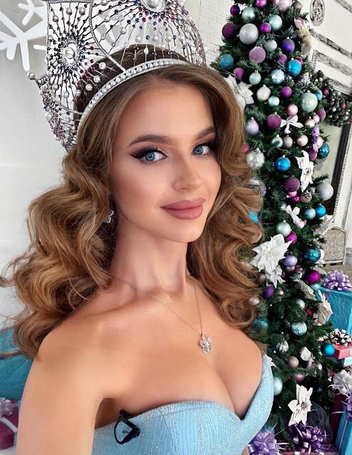 a woman wearing a tiara next to a christmas tree