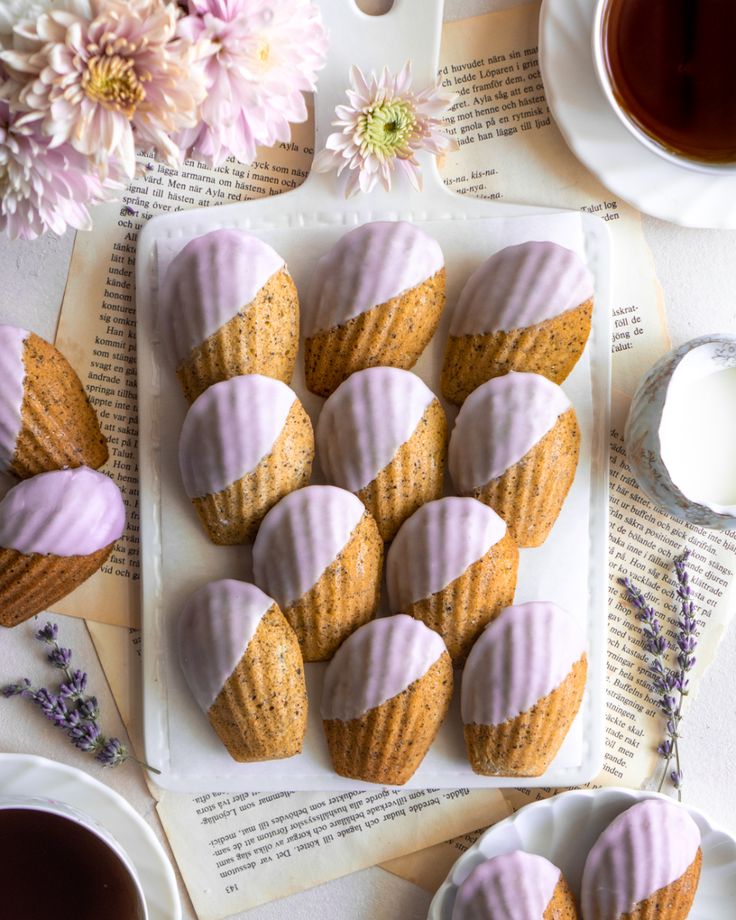 lavender cupcakes on a plate with coffee and flowers in the background, next to an open book