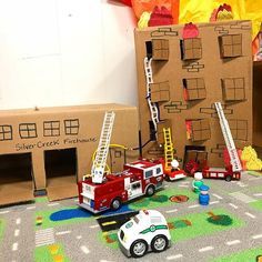 there is a toy fire truck next to some cardboard boxes and other toys on the floor