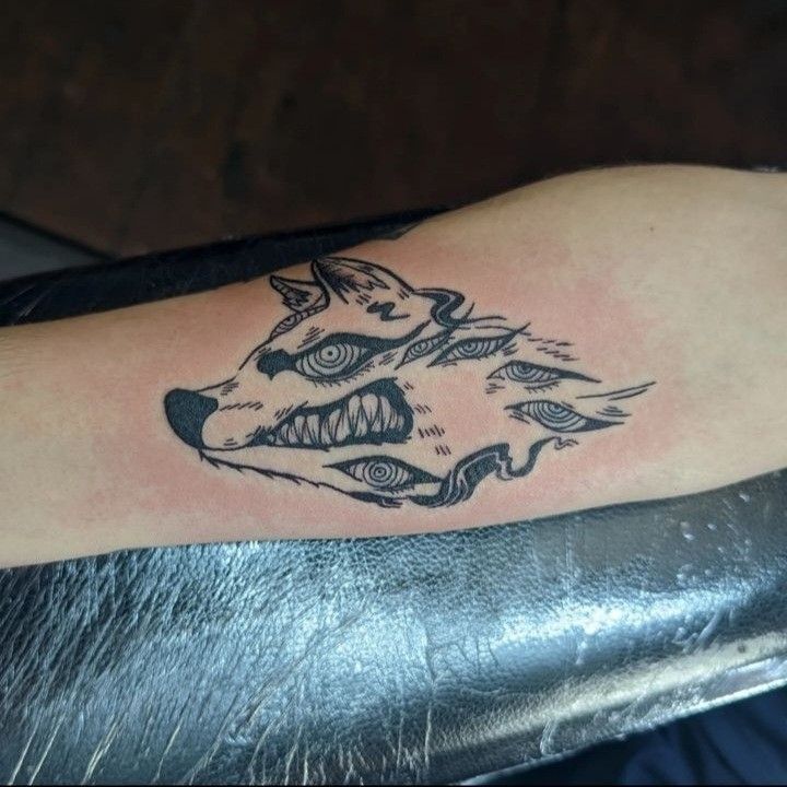 a tattoo on the arm of a person with a wolf's head and feathers