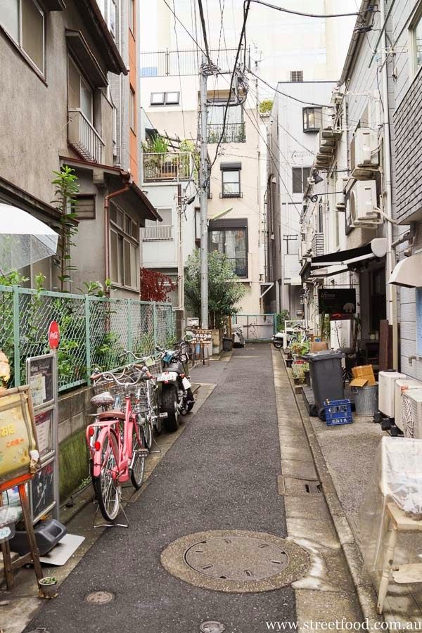 an alleyway with several bicycles parked on the side and buildings in the background,