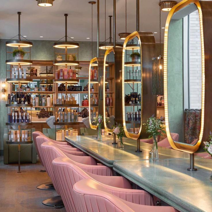 the interior of a bar with pink chairs and gold mirrors hanging from the ceiling above it