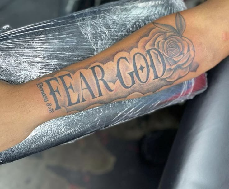 a man's arm with the word fear god tattooed on it and a rose