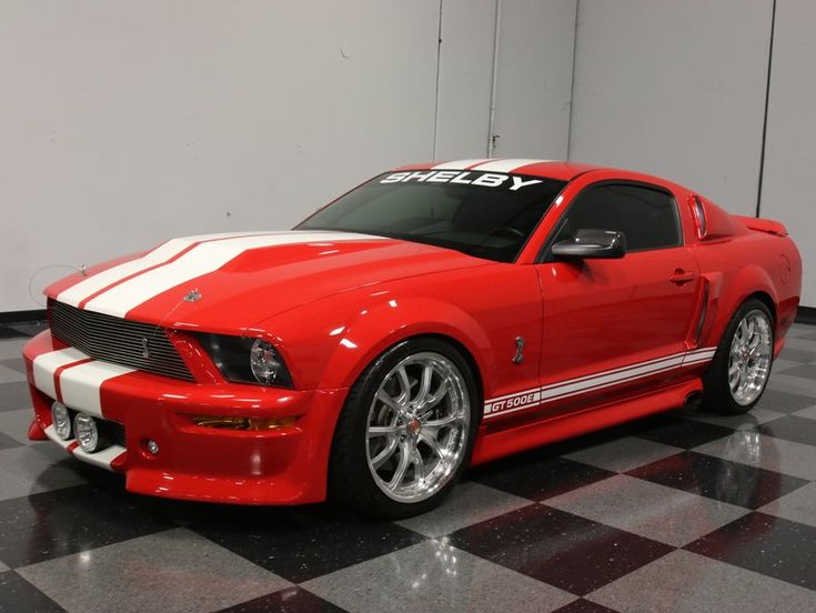 a red and white mustang car on a black and white checkered floor