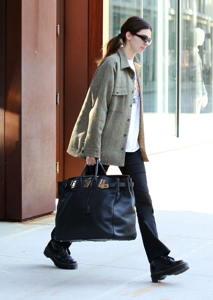 a woman walking down the street carrying a black bag