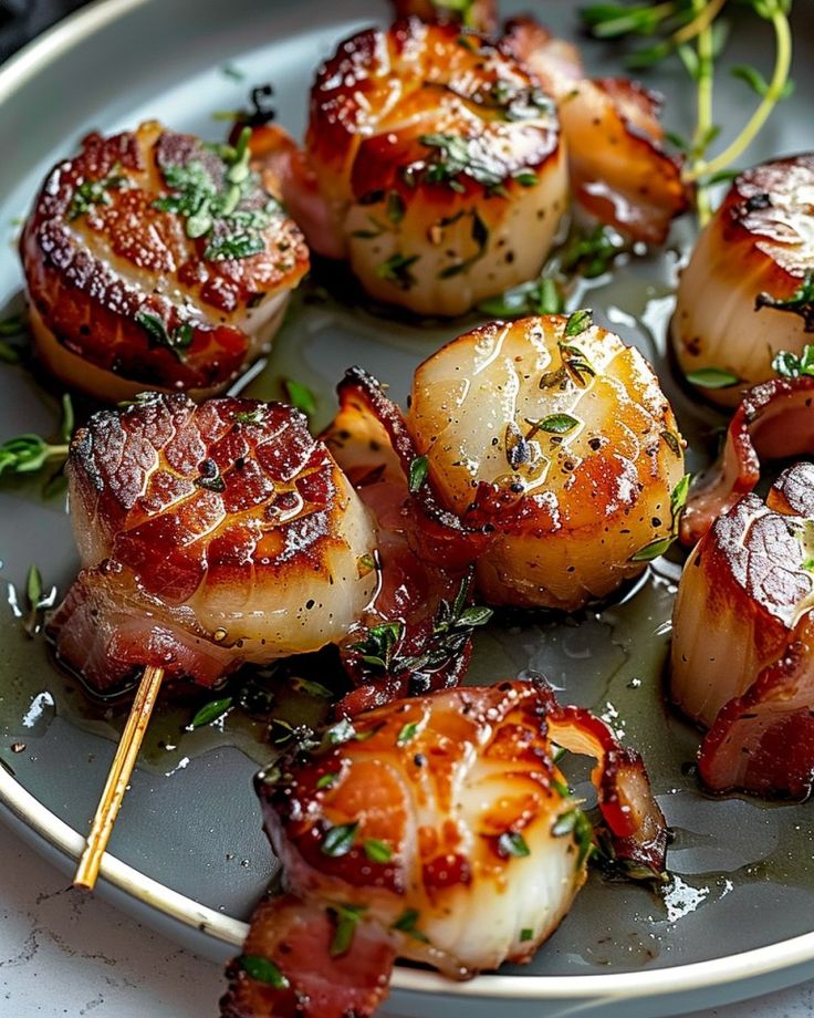 some food is sitting on a plate with toothpicks in it and garnished with herbs