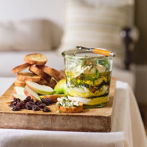 a wooden cutting board topped with fruit and veggies on top of a table