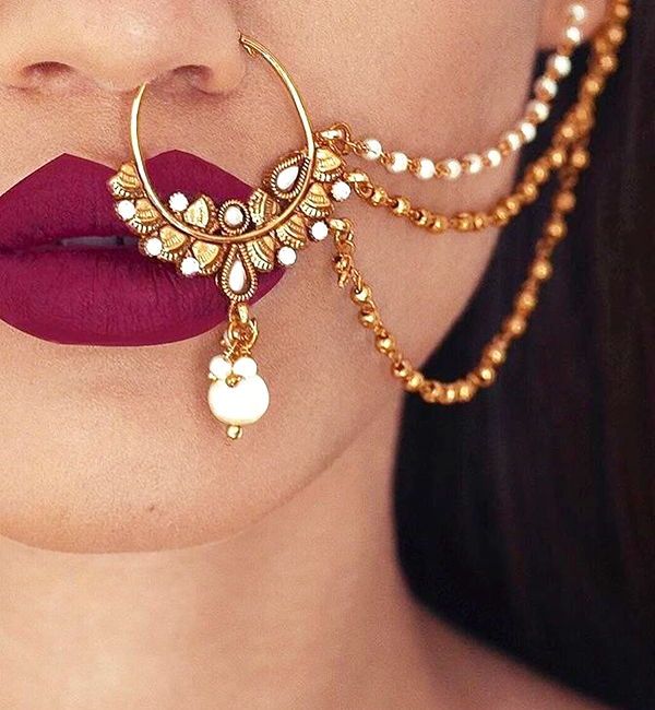 a close up of a person with red lipstick and gold jewelry on her face,