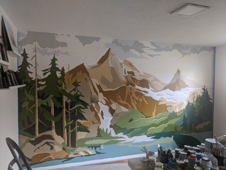 the wall is painted with an image of mountains and trees, along with other paint supplies