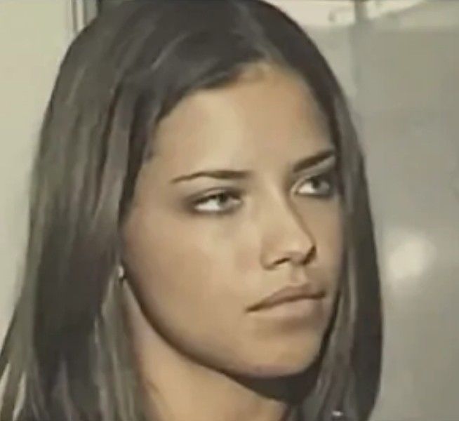 a close up of a woman with long hair and piercings on her ear, looking at the camera