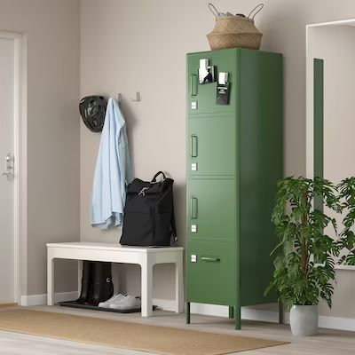 a green locker next to a white bench with a black bag and coat on it